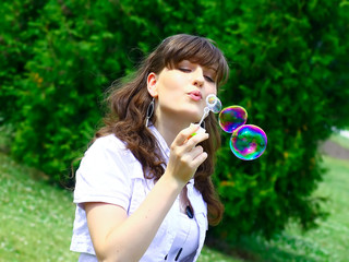 Young girl blowing soap bubbles in autumn park