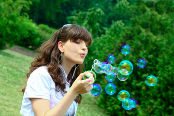 Young girl blowing soap bubbles in autumn park