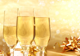 Glasses of champagne with golden decoration on background