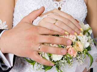 Hands and rings on wedding bouquet