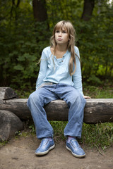 Obraz premium serious little girl nine years old sitting on bench in park