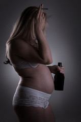 Pregnant woman with bottle of alcohol and cigarette