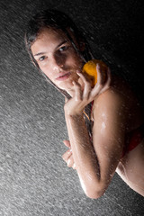 Fototapeta na wymiar pretty teen with orange in water studio