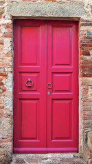 Wooden closed pink door with brick wall around it.