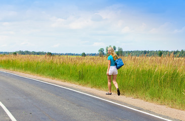 Beautiful young woman with luggage on road..