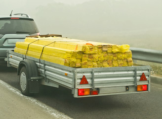 Auto car trailer laden with wooden planks building material at foggy road