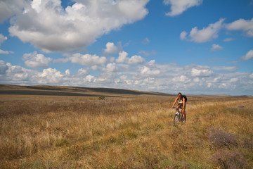 Women with bike on meadow on sky background