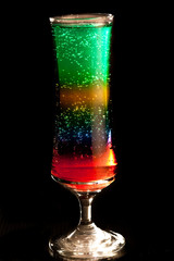 Layers of different coloured liquid in tall glass