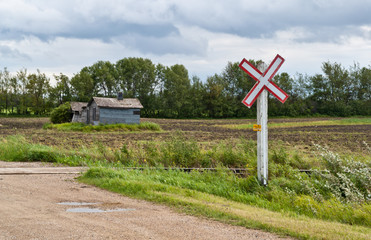 A sign marks a dirt road railway crossing on the prairies
