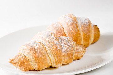 fresh croissants on white plate with powdered sugar