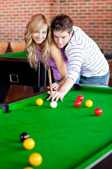 Affectionate boyfriend learning his girlfriend how to play pool