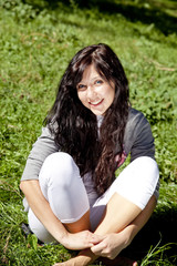 Fototapeta premium Portrait of beautiful brunette girl with blue eyes on green gras
