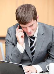 Concentrated businessman using his laptop while talking on phone