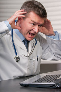 Doctor gestures in despair at information on laptop