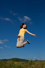 Girl jumping, running against blue sky