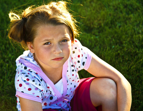 Beautiful young girl unhappy on the grass