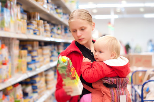 Young Mother With Baby Daughter Shopping In Supermarket