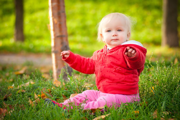 young adorable cheerful baby sit in park on green grass play wit