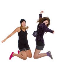 Two young teenage girls with trendy stylish clothes jumping.