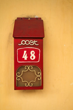 Red letterbox against cream wall