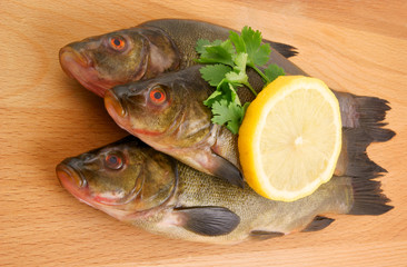 Raw fish with lemon and parsley on wooden background