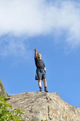 A young man stands on a cliff top