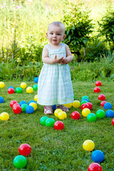 Fototapeta na wymiar babygirl is playing with balls on green grass