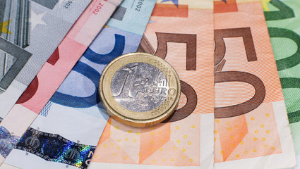 One Euro coin across banknotes