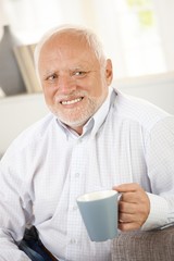 Smiling old man having coffee