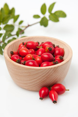 Rose hip branch with leaves in wooden bowl