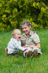 Cute brother and sister playing on the green grass
