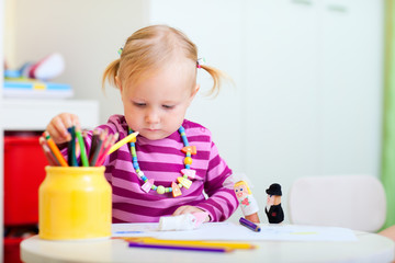 Naklejka premium Toddler girl coloring with pencils
