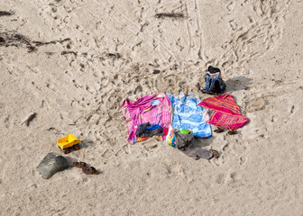 Fototapeta na wymiar Trzy ręczniki plażowe porzucone na piasku