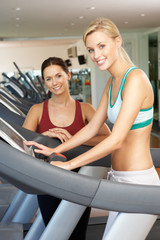 Fototapeta na wymiar Woman Working With Female Personal Trainer On Running Machine In