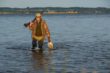 hunter wading with a duck in his hand