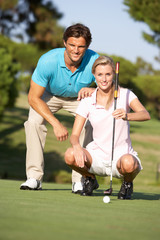 Fototapeta premium Couple Golfing On Golf Course Lining Up Putt On Green