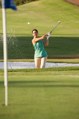 Female Golfer Playing Bunker Shot On Golf Course