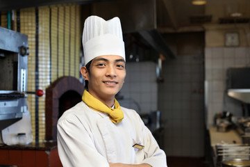 portrait young handsome asian male chef standing and posing in the restaurant or hotel kitchen smiling expression face