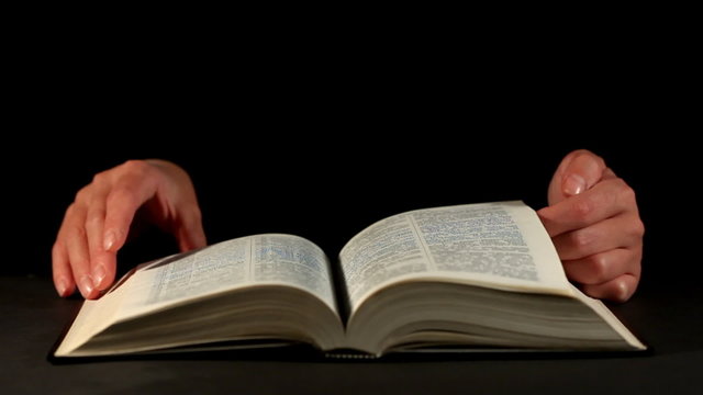 Hands and book over dark background