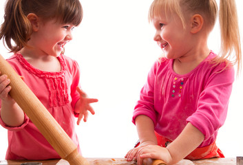 two little girls with rolling pins baking cookies