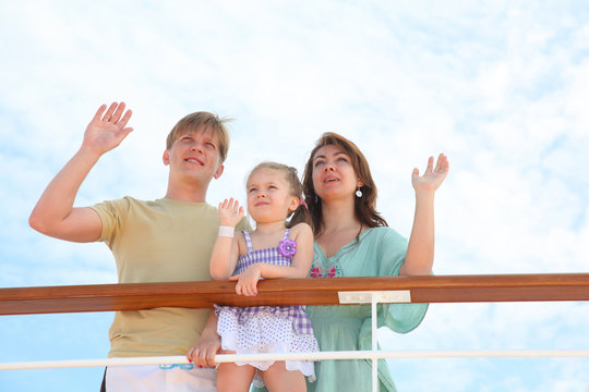 mom dad and daughter wave by hands to ship