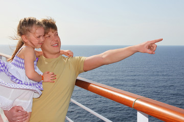 father standing on cruise liner deck, carrying his daughter and