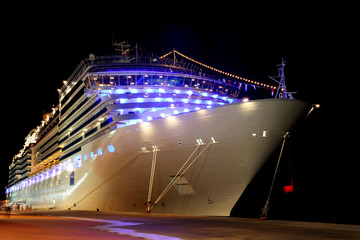 big modern cruise liner with lamps standing in dock at night