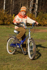 Fototapeta na wymiar Boy on bicycle in autumn park on sunny day.