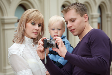 Man shows girl with baby picture with digital camera.
