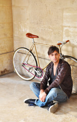 Young man sitting in front of his fixed-gear bicycle