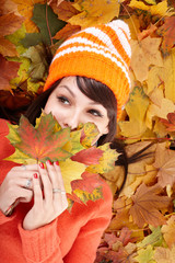 Young woman in autumn orange leaves.