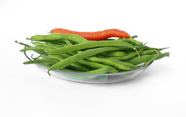 Glass dish with green beans on a white background