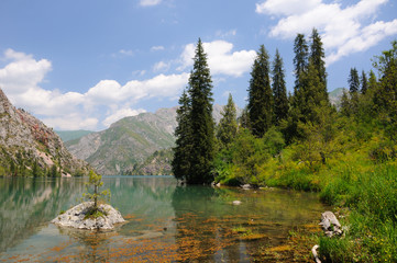 Colorful Sary-Chelek Lake with mountains, sky and clouds