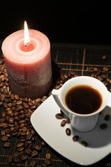 Cup of the fresh coffee and candle on the table.